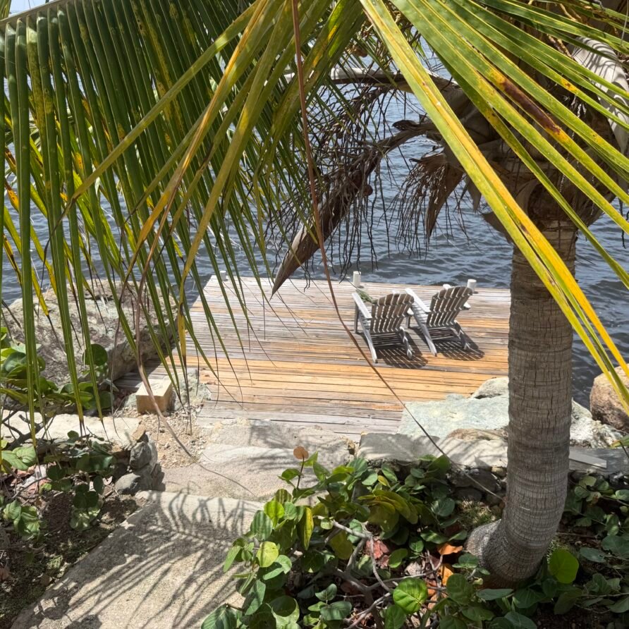 Villa bedroom with king bed, air conditioning, and private balcony overlooking the water.