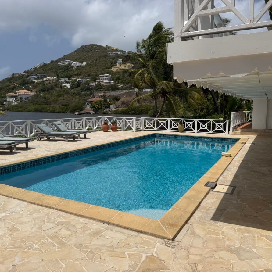 Spacious waterfront villa with a large pool deck, lounge chairs, and panoramic sea views.